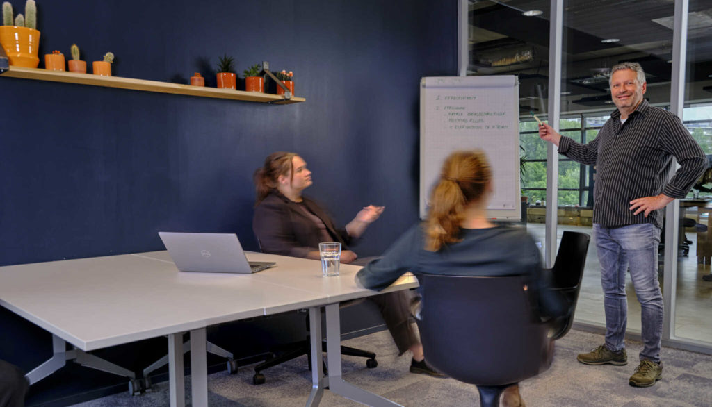 Een man geeft een presentatie terwijl twee vrouwen kijken