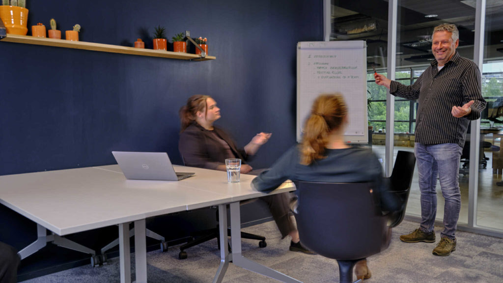 Een man geeft een presentatie terwijl twee vrouwen kijken