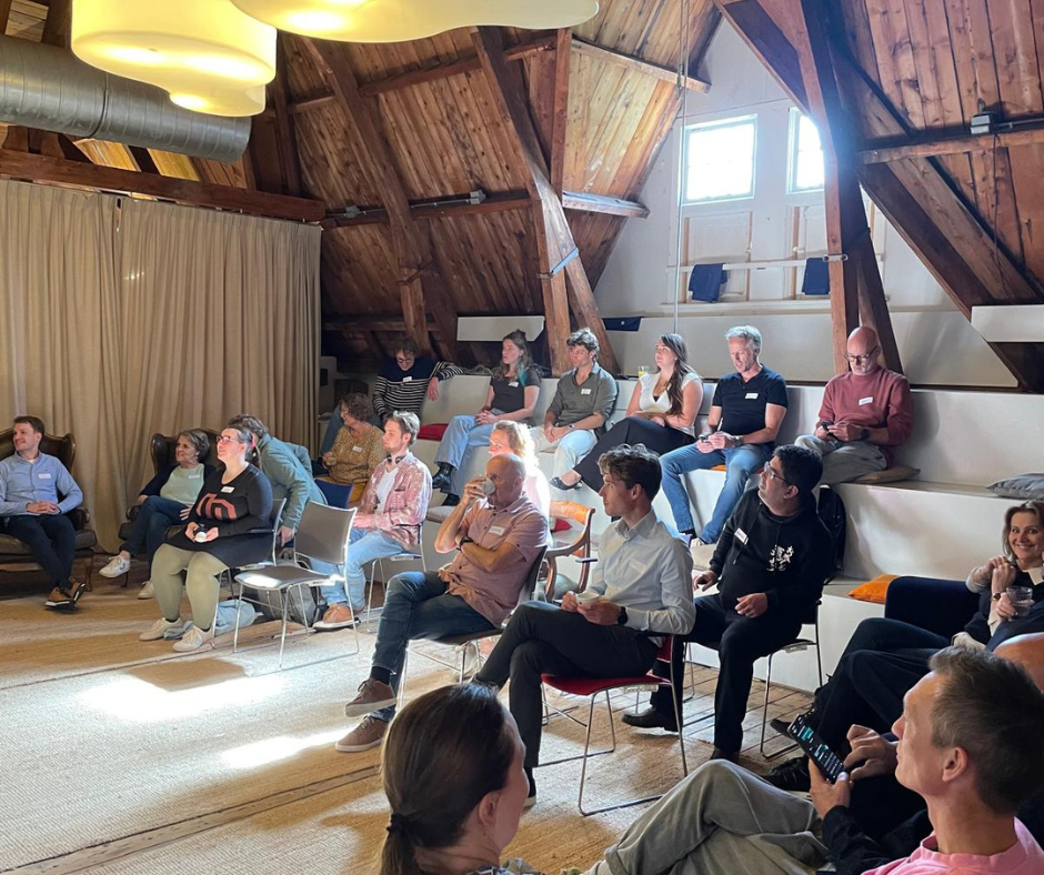 Foto van mensen die naast en achter elkaar zitten en dezelfde kant op kijken. De foto is genomen tijdens de Deep Democracy.