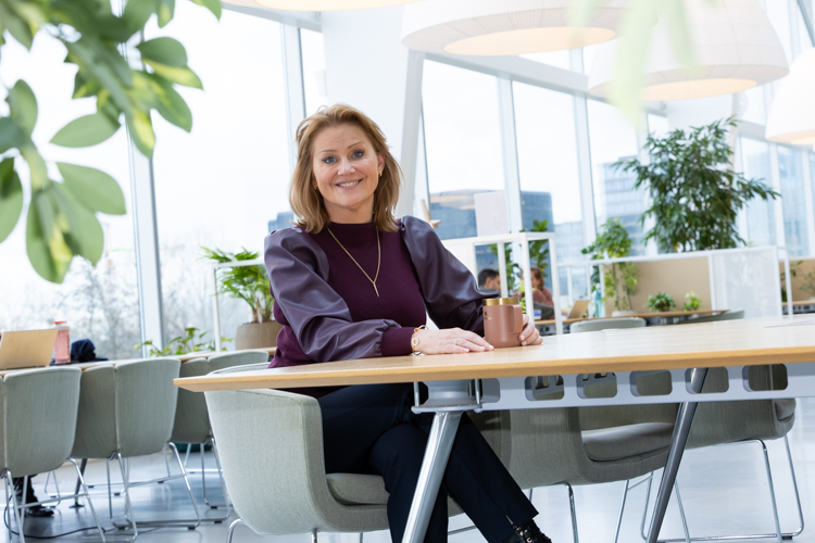 Een foto van Brechtje die naar de camera kijkt. Ze zit achter een tafel.
